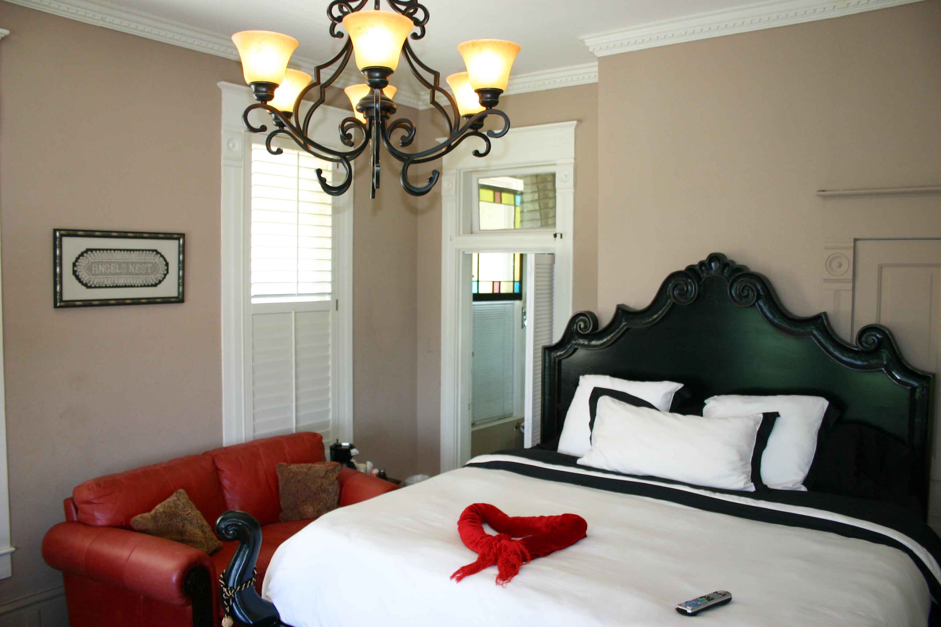 A bedroom with a bed, couch and chandelier.